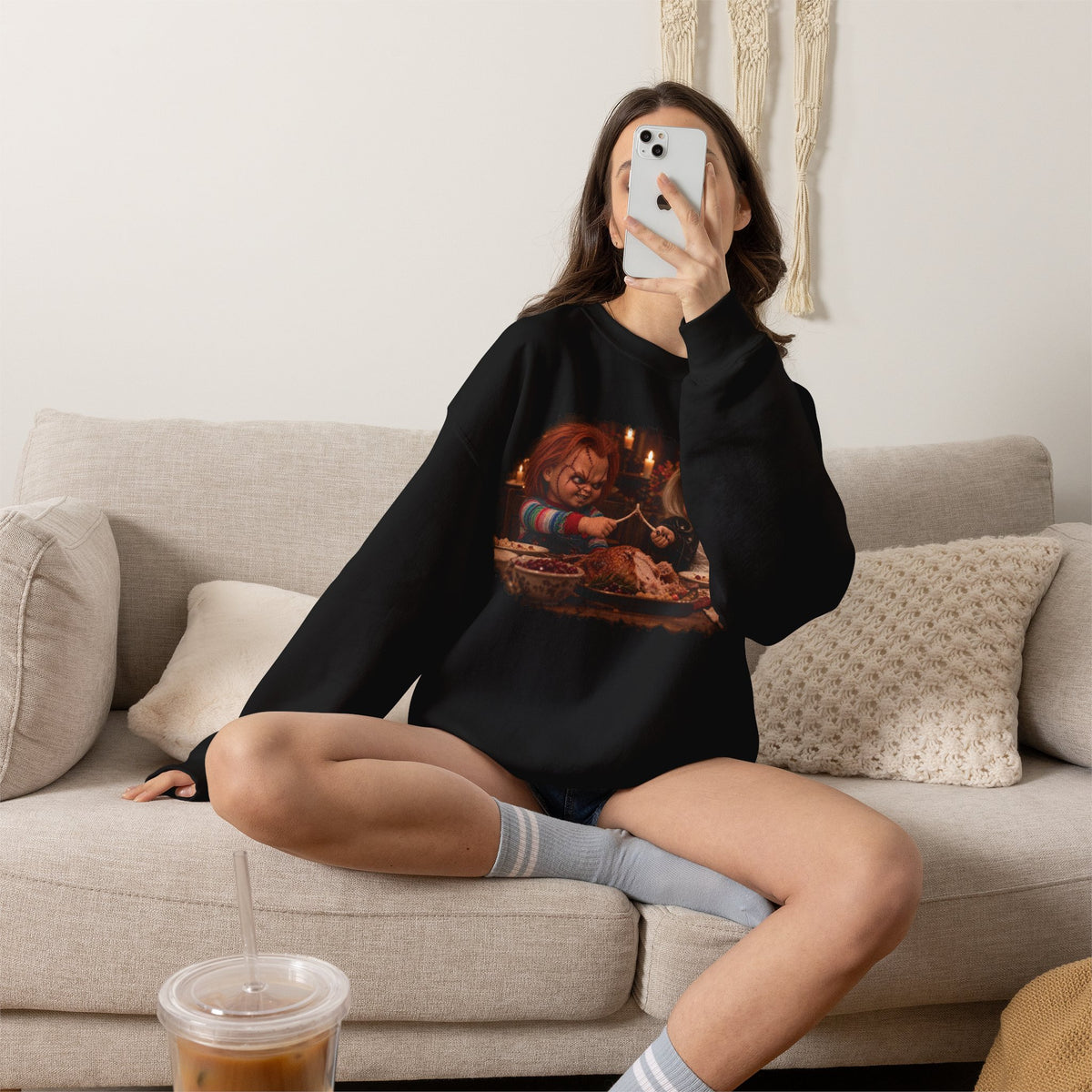 Woman wearing the Chucky & Tiffany Thanksgiving wishbone sweatshirt in Black, sitting on a couch