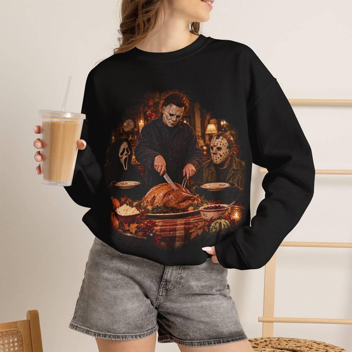 Woman wearing the Michael Myers, Ghostface and Jason Thanksgiving sweatshirt in Black, holding an iced coffee