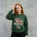 Model wearing Mistletoe Motel Christmas Sweatshirt against a cement wall