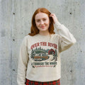 Model wearing Over the River and Through the Woods Christmas Sweatshirt against a cement wall