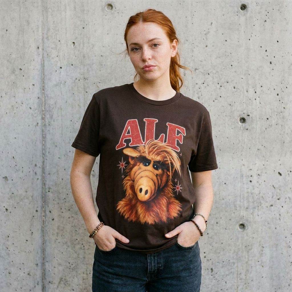 Model wearing ALF Graphic Tee – Retro 80s TV Shirt against a cement wall