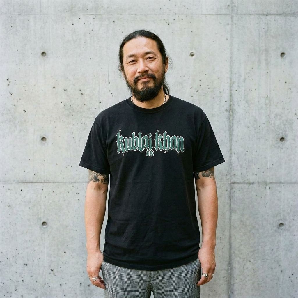 Model wearing Kublai Khan Band Tee – Retro Graphic Concert Shirt against a cement wall