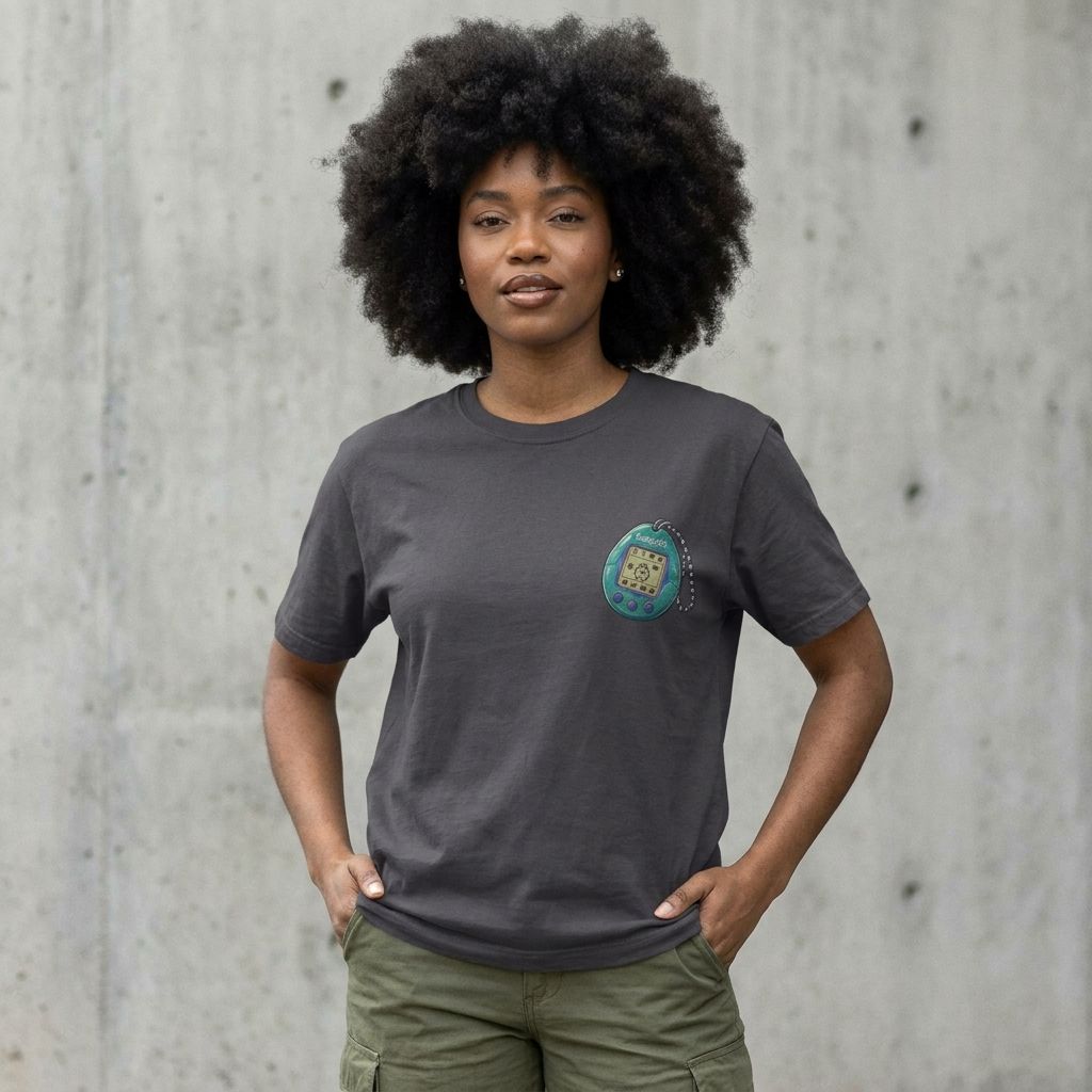 Model wearing Tamagotchi Graphic Tee – Minimal Retro 90s Pocket Tee against a cement wall