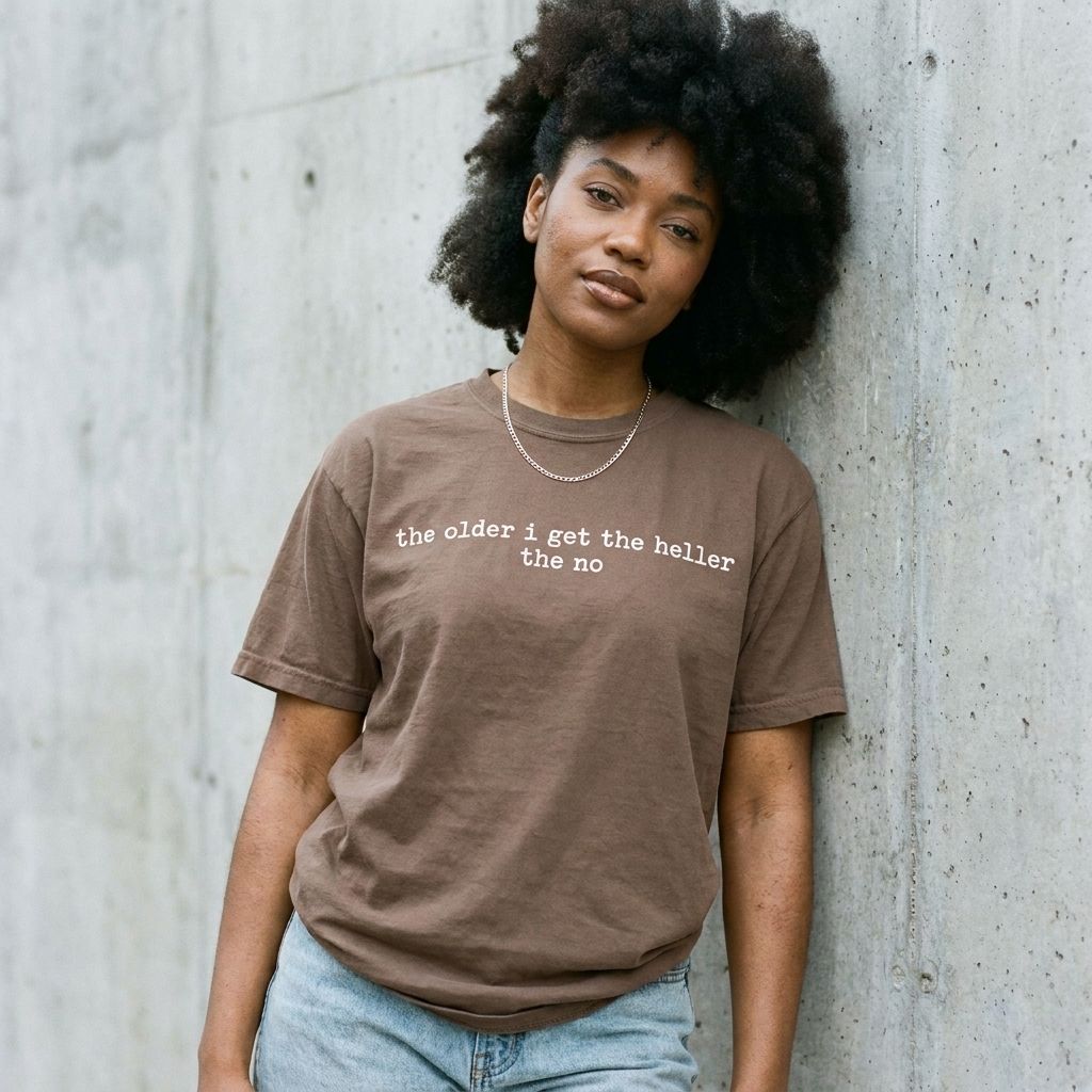 Model wearing The Older I Get The Heller The No Graphic Tee against a cement wall