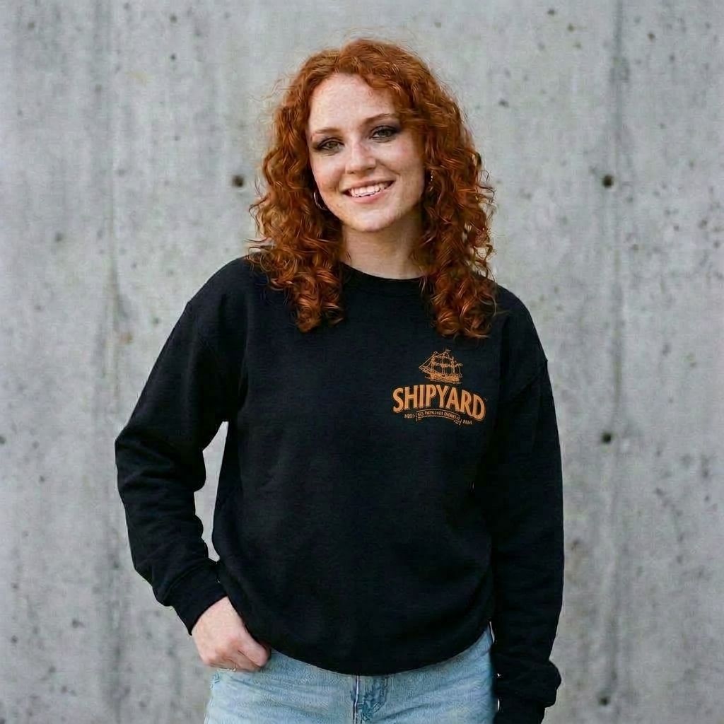 Model wearing Shipyard Pumpkinhead Ale Sweatshirt against a cement wall