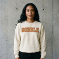 Model wearing Gobble Thanksgiving Crewneck Sweatshirt against a cement wall
