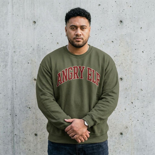 Man wearing the Angry Elf funny Christmas sweatshirt against a cement wall