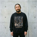 Man wearing the Krampusnacht winter forest sweatshirt against a cement wall