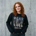 Woman wearing the Yule Cat Christmas sweatshirt against a cement wall