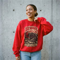 Woman wearing the Beware the Yule Cat horror poster Christmas sweatshirt against a cement wall