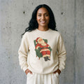 Woman wearing the vintage Santa Claus in armchair Christmas sweatshirt against a cement wall