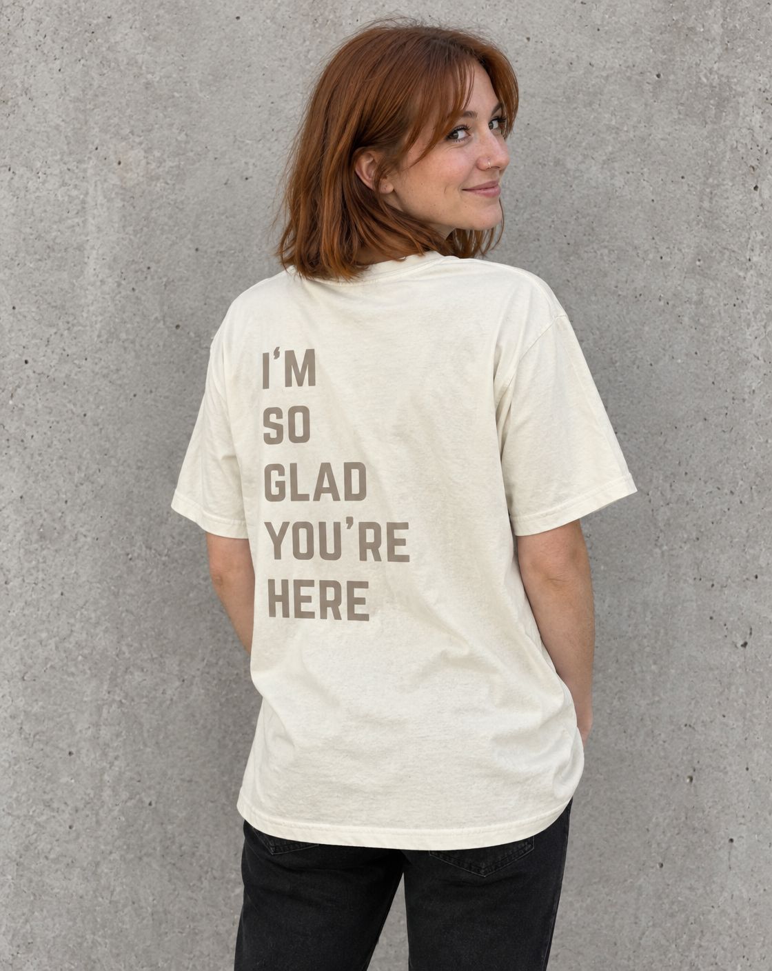 Model wearing the ivory I'm So Glad You're Here suicide awareness t-shirt, back view