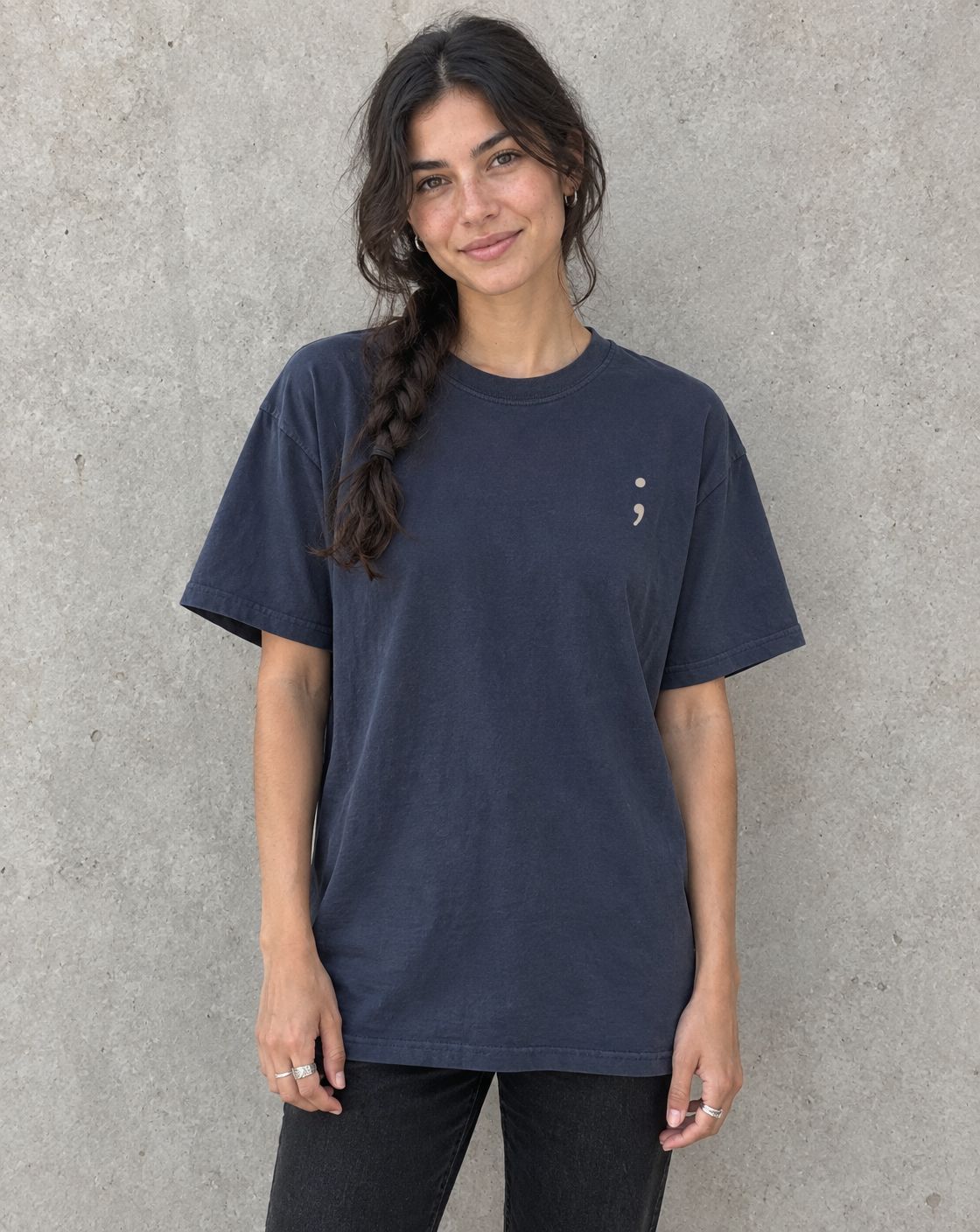 Model wearing the navy Be the Reason Someone Feels Less Alone t-shirt, front view with small semicolon