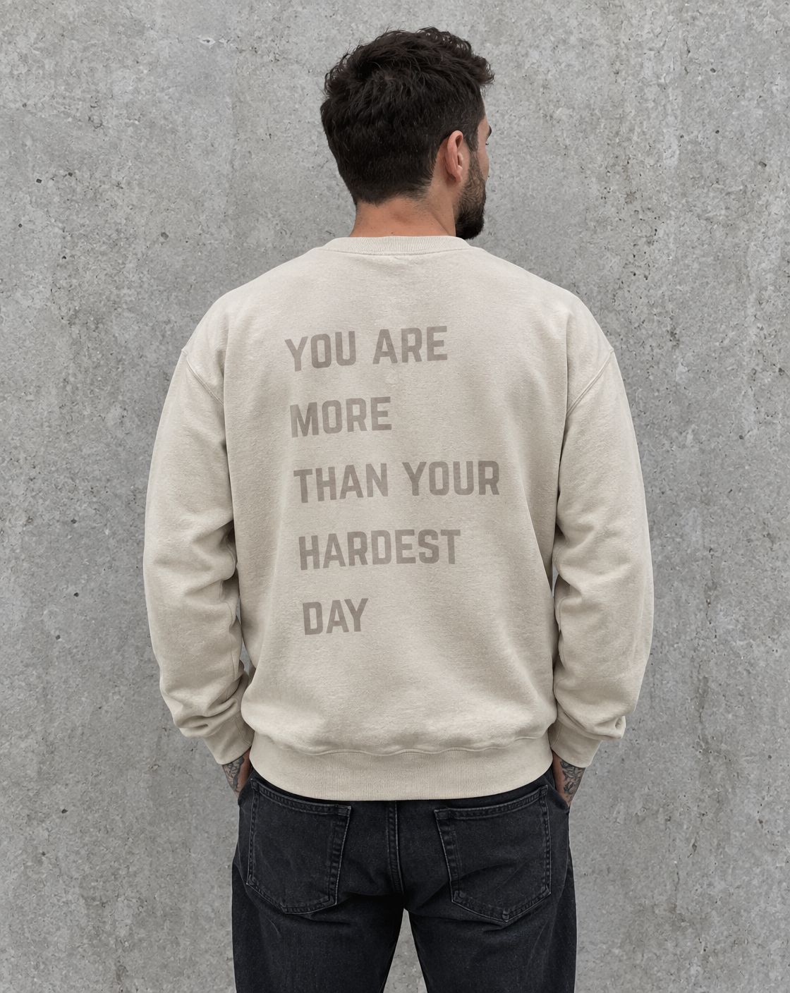 Model wearing the sand You Are More Than Your Hardest Day suicide awareness crewneck sweatshirt, back view