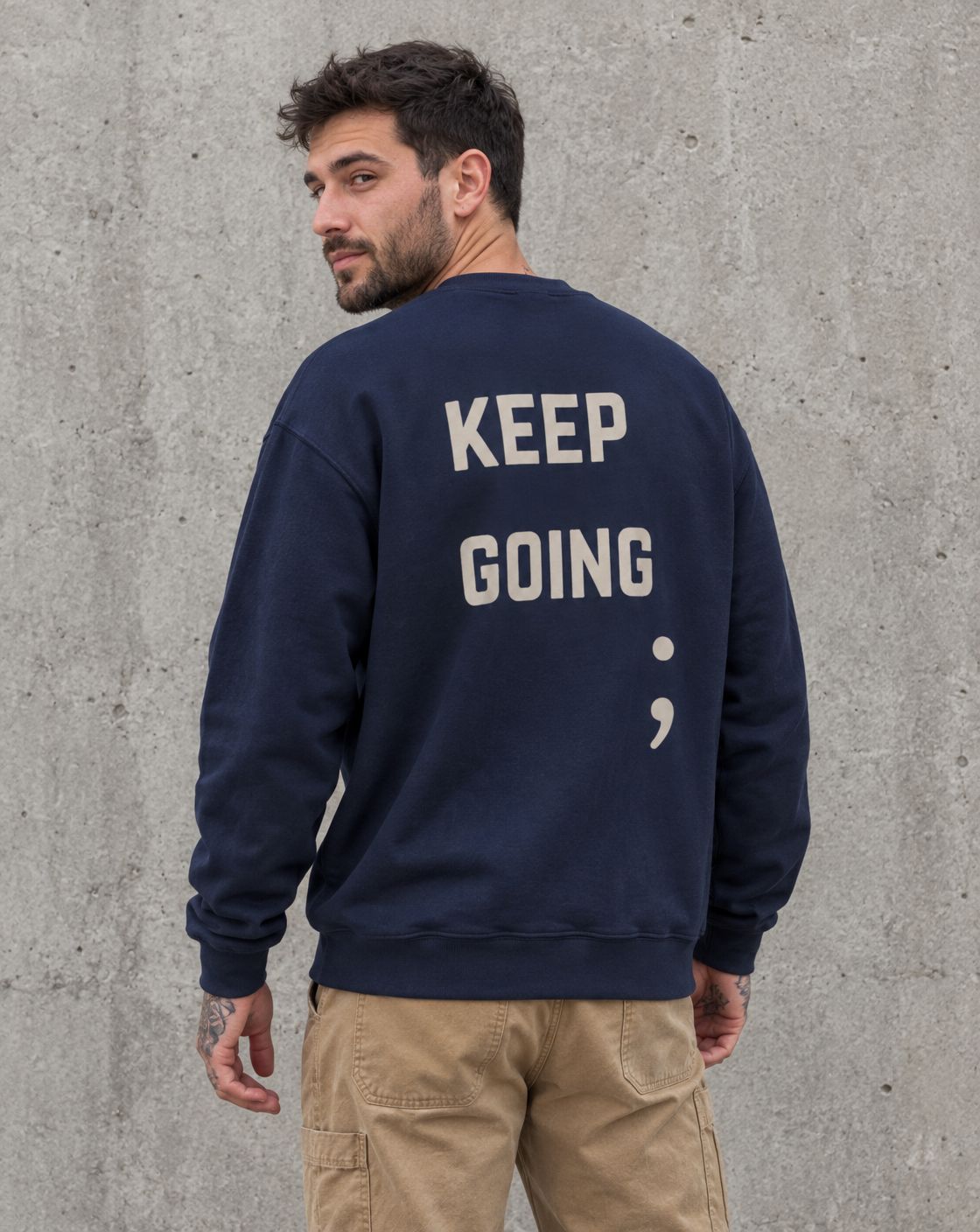 Model wearing the navy Keep Going semicolon suicide awareness crewneck sweatshirt, back view