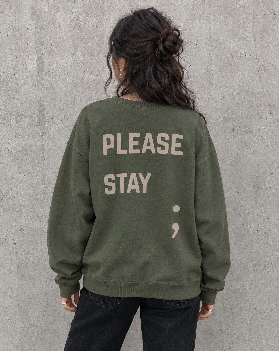Model wearing the military green Please Stay; suicide awareness crewneck sweatshirt, back view