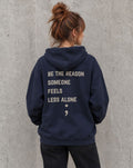 Model wearing the navy Be the Reason Someone Feels Less Alone suicide awareness pullover hoodie, back view