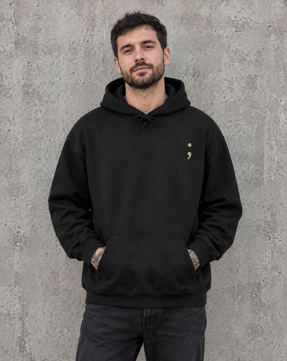 Model wearing the black Stay for Tomorrow pullover hoodie, front view with small semicolon