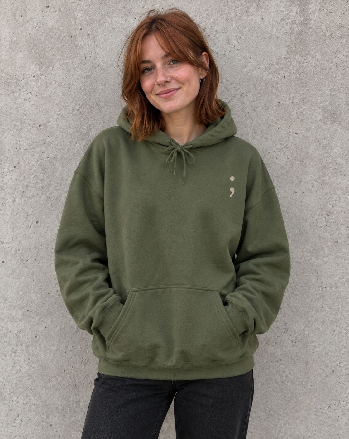 Model wearing the military green Please Stay; pullover hoodie, front view with small semicolon