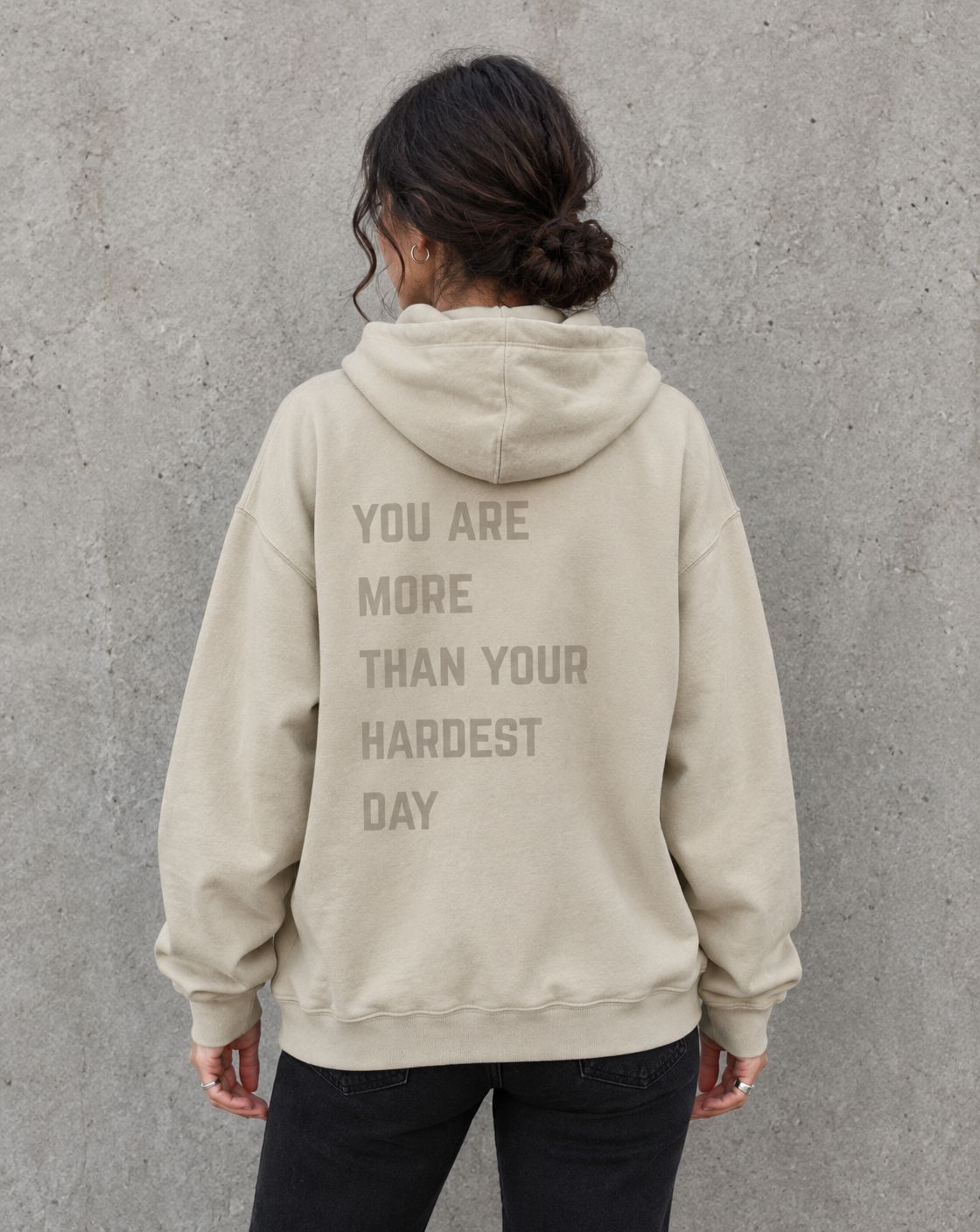 Model wearing the sand You Are More Than Your Hardest Day suicide awareness pullover hoodie, back view