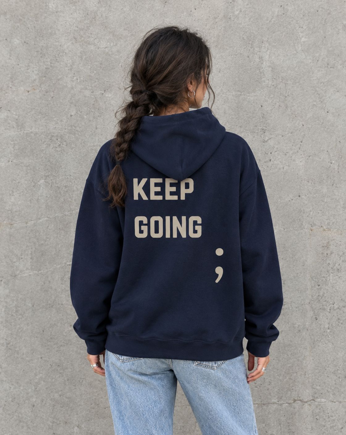 Model wearing the navy Keep Going semicolon suicide awareness pullover hoodie, back view