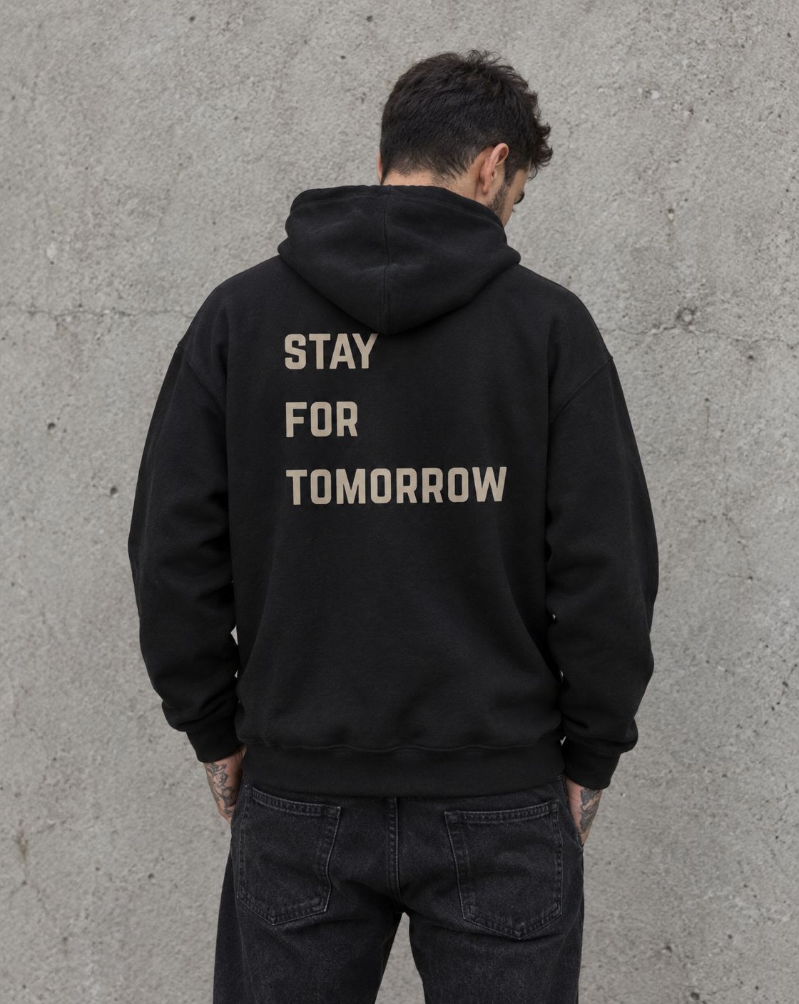 Model wearing the black Stay for Tomorrow suicide awareness pullover hoodie, back view