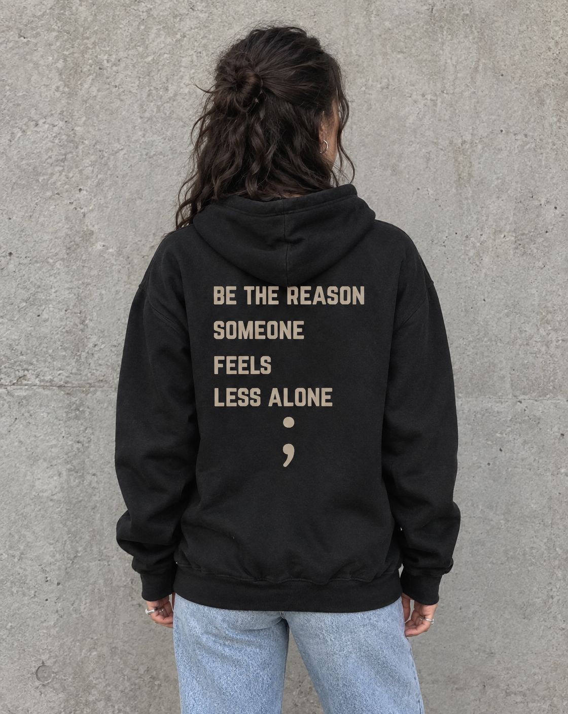 Model wearing the black Be the Reason Someone Feels Less Alone suicide awareness zip up hoodie, back view