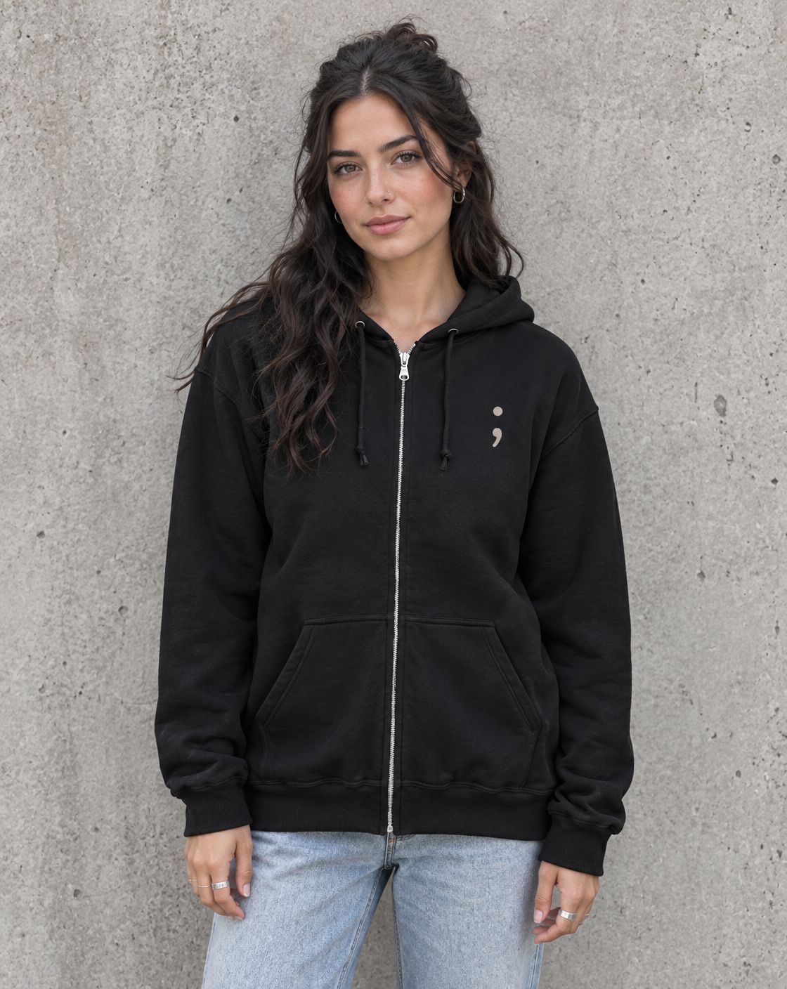 Model wearing the black Be the Reason Someone Feels Less Alone zip up hoodie, front view with small semicolon