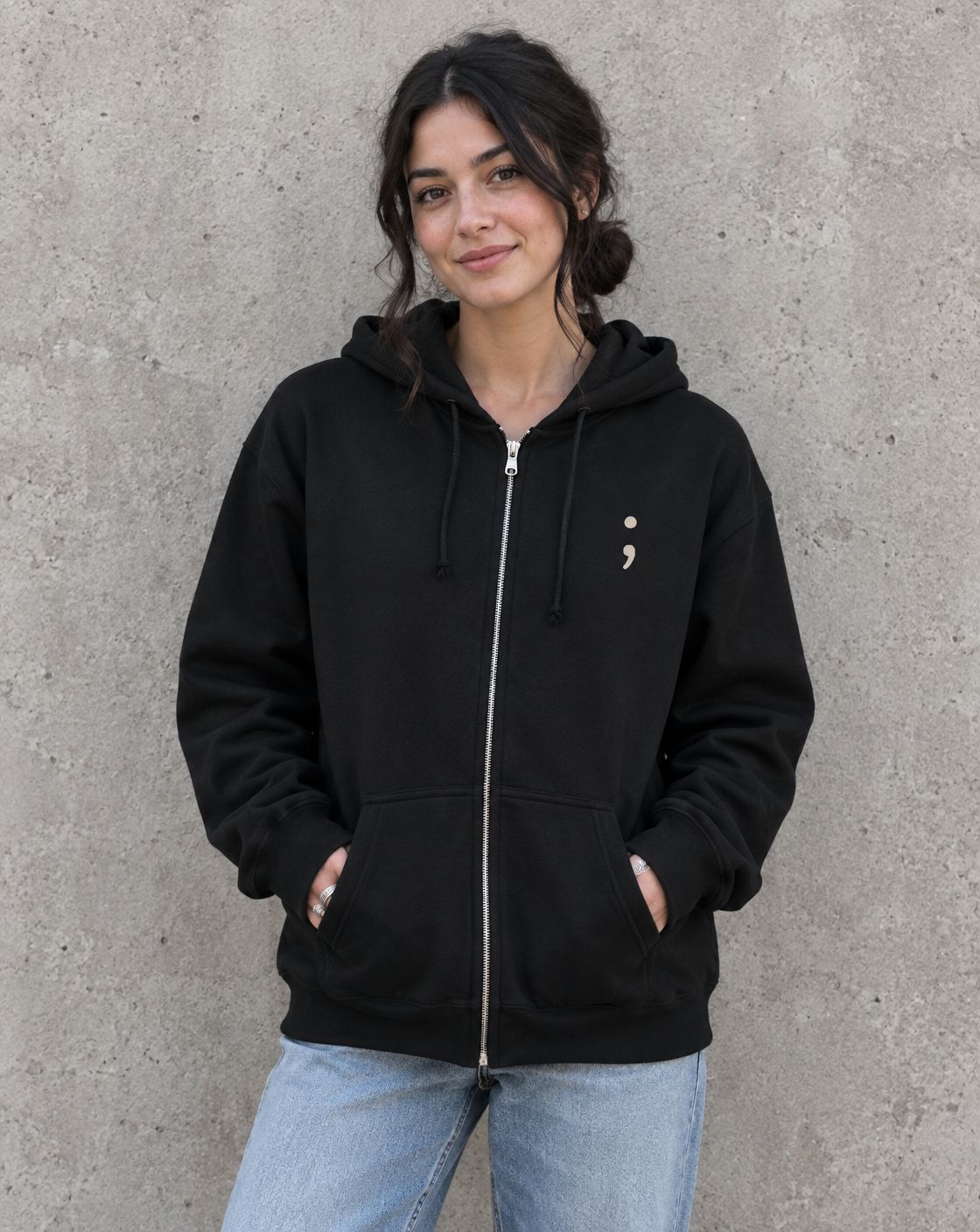 Model wearing the black You Belong Here zip up hoodie, front view with small semicolon