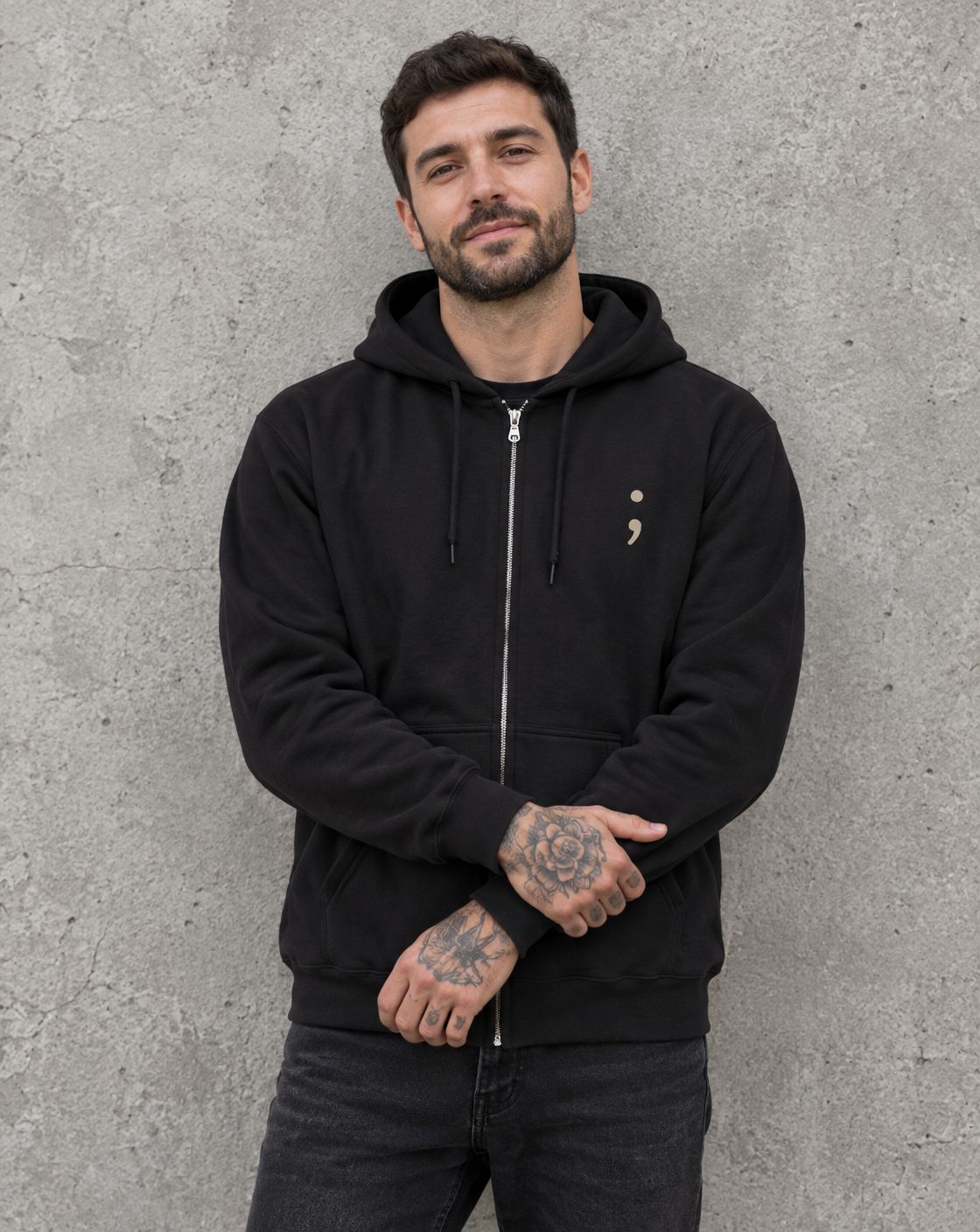 Model wearing the black Keep Going zip up hoodie, front view with small semicolon