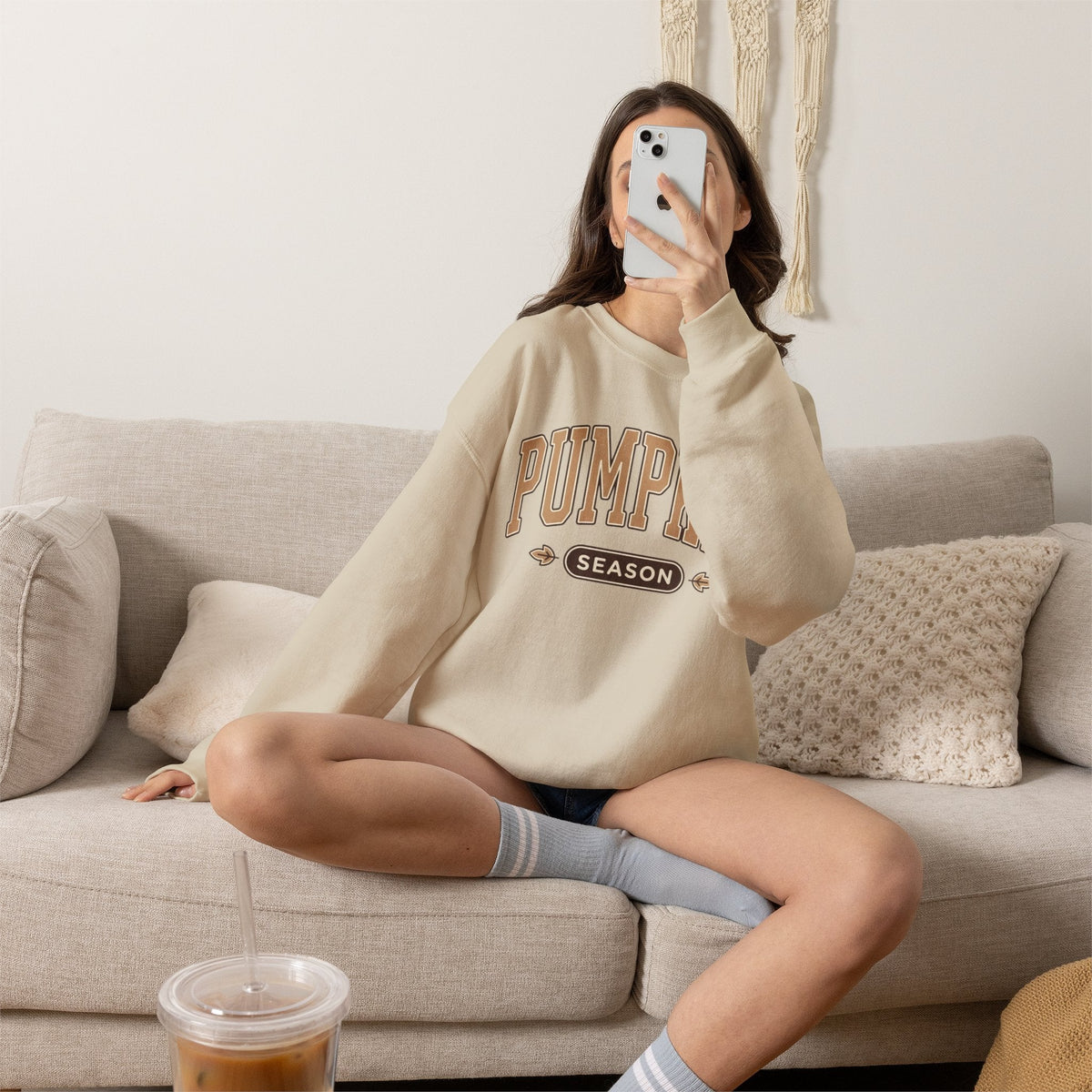 Wicked Thread Society beige crewneck sweatshirt with vintage Pumpkin Season graphic worn by a woman on a cozy sofa.