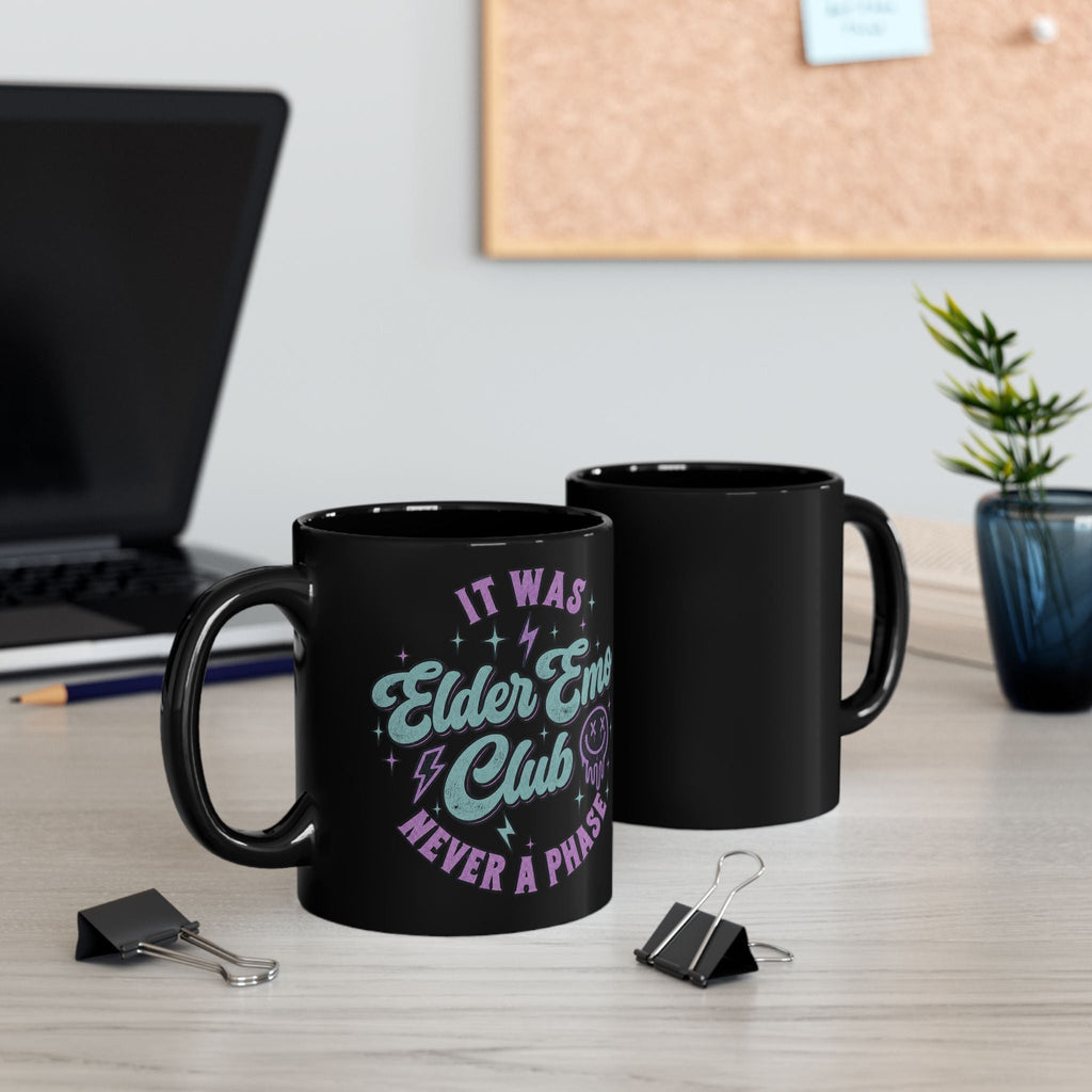 Wicked Thread Society black ceramic coffee mug featuring Elder Emo Club neon typography on a desk with office decor.