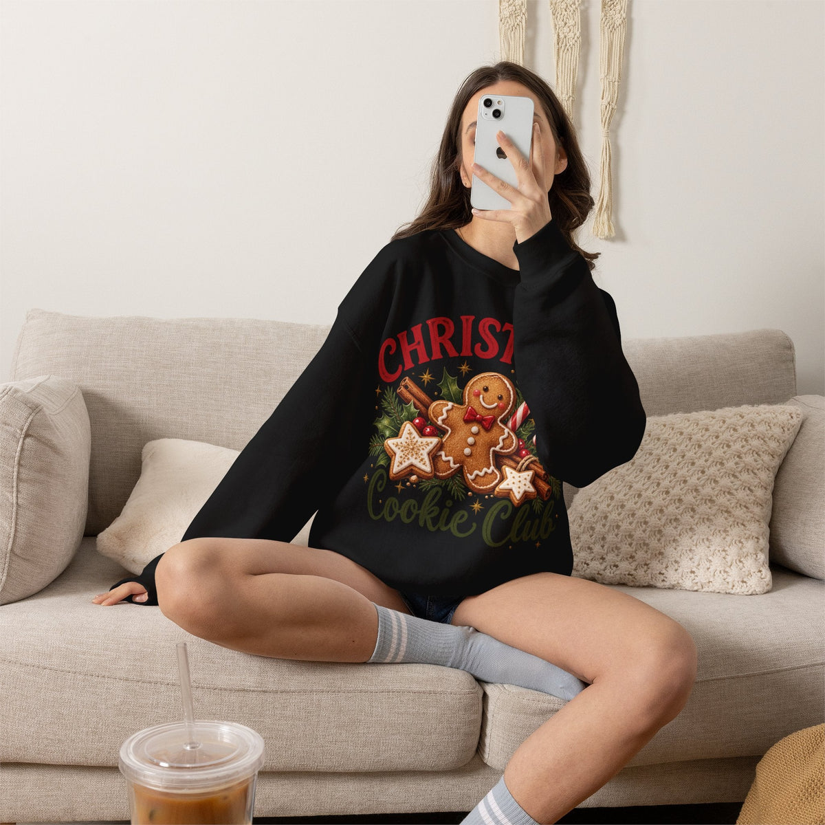 Wicked Thread Society black crewneck sweatshirt with gingerbread man graphic, sitting on a beige couch.