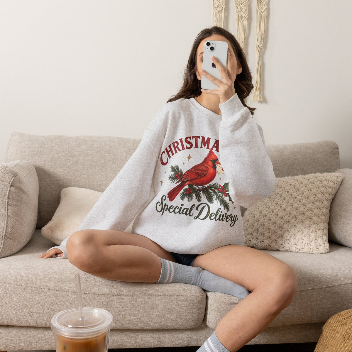 Wicked Thread Society grey crewneck sweatshirt featuring a cardinal bird illustration and Christmas text on a sofa