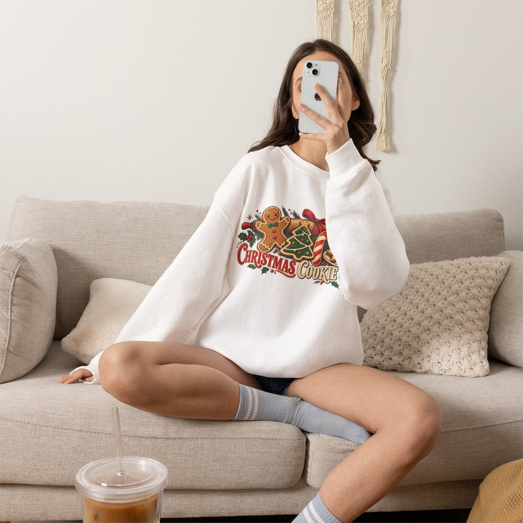 Wicked Thread Society white crewneck sweatshirt with Christmas cookie graphic, worn by a woman sitting on a sofa.