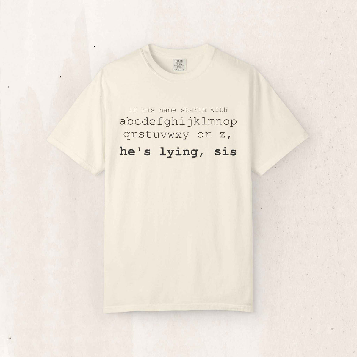 He's Lying, Sis Tee – Funny Alphabet Typography Shirt – Ivory