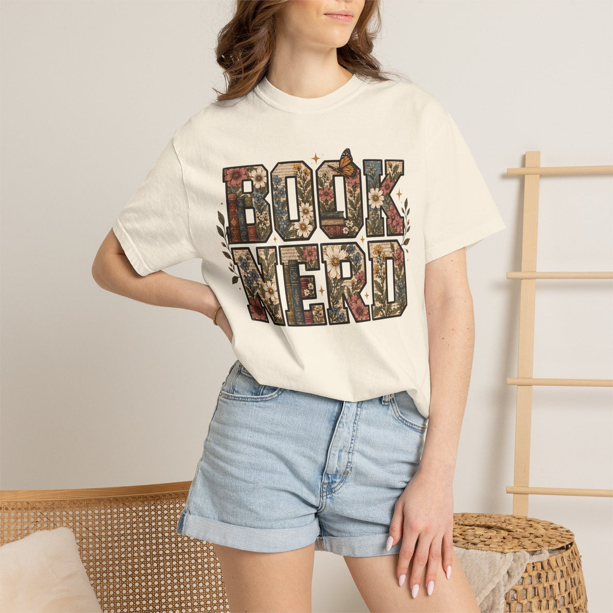 Wicked Thread Society cream graphic tee with floral Book Nerd lettering and butterfly accents worn with denim shorts.