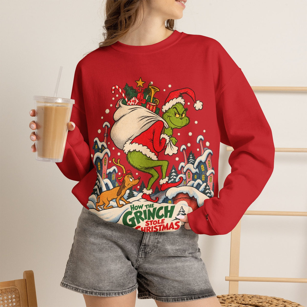 Wicked Thread Society red crewneck sweatshirt featuring a vintage Grinch illustration on a woman holding iced coffee