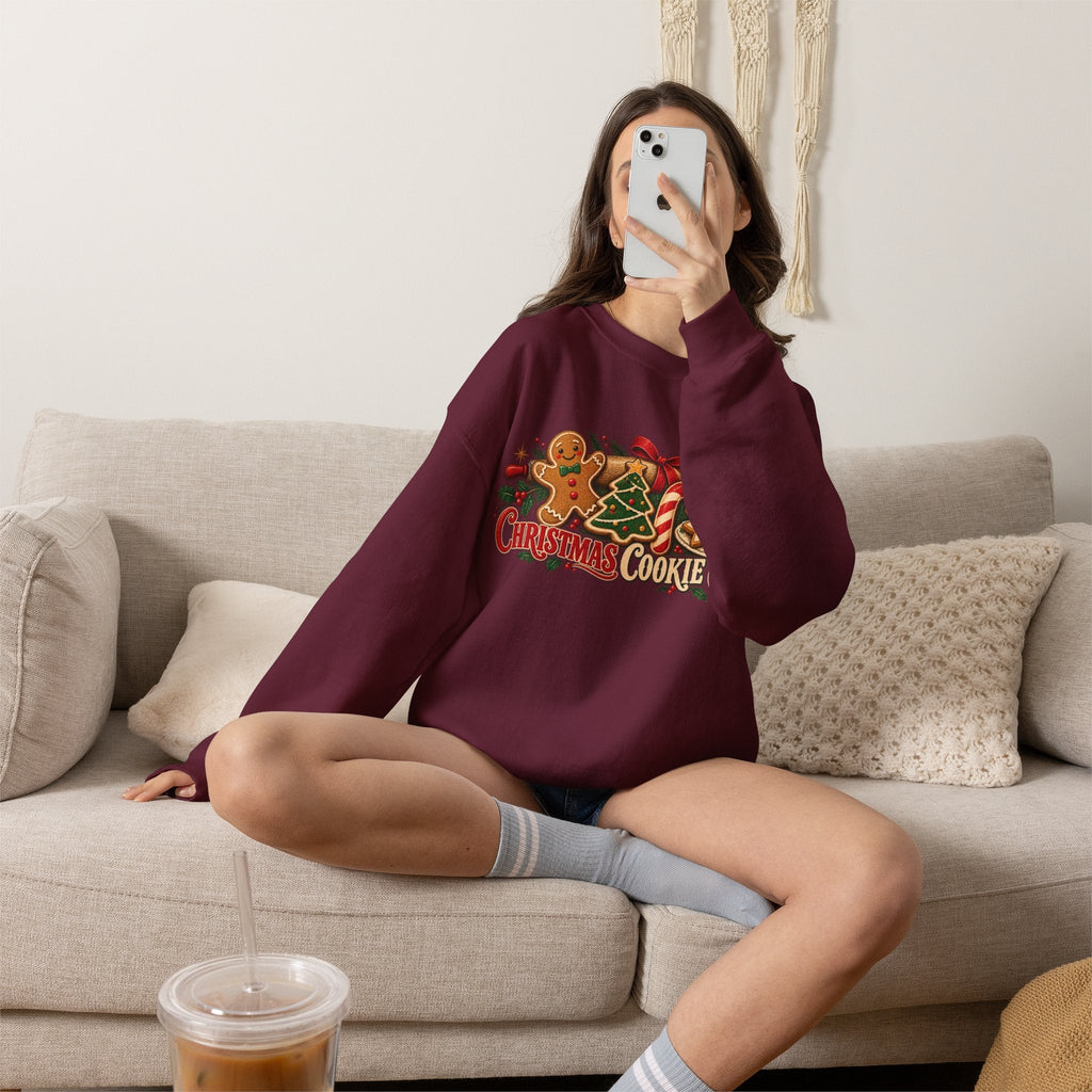 Wicked Thread Society maroon crewneck sweatshirt with Christmas cookie graphic, worn by a woman sitting on a sofa.