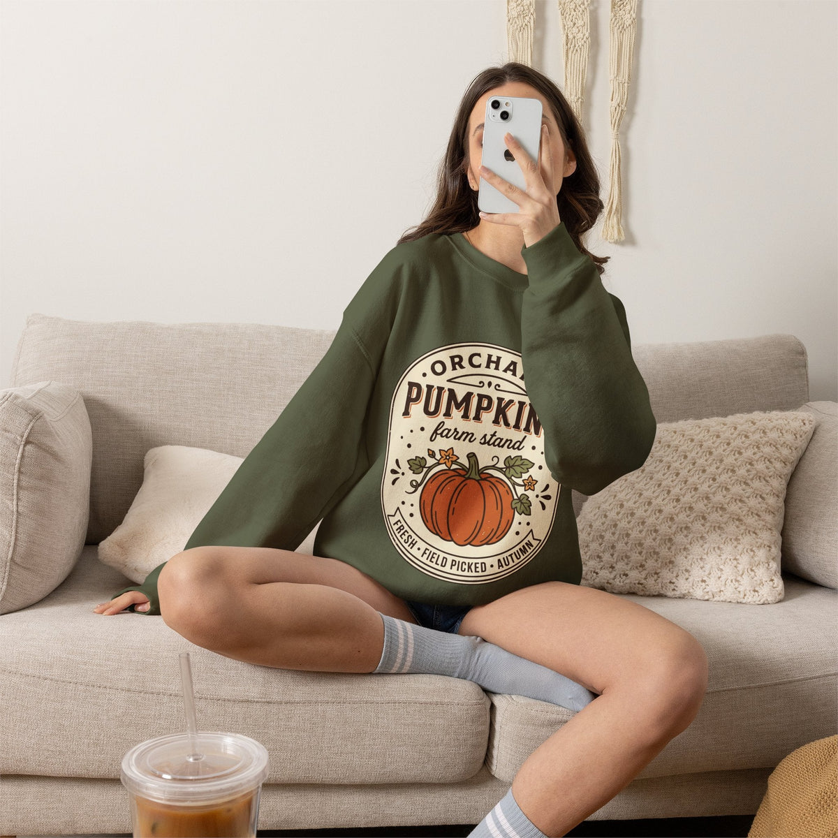 Wicked Thread Society olive green crewneck sweatshirt with a vintage pumpkin farmstand graphic, worn by a woman.
