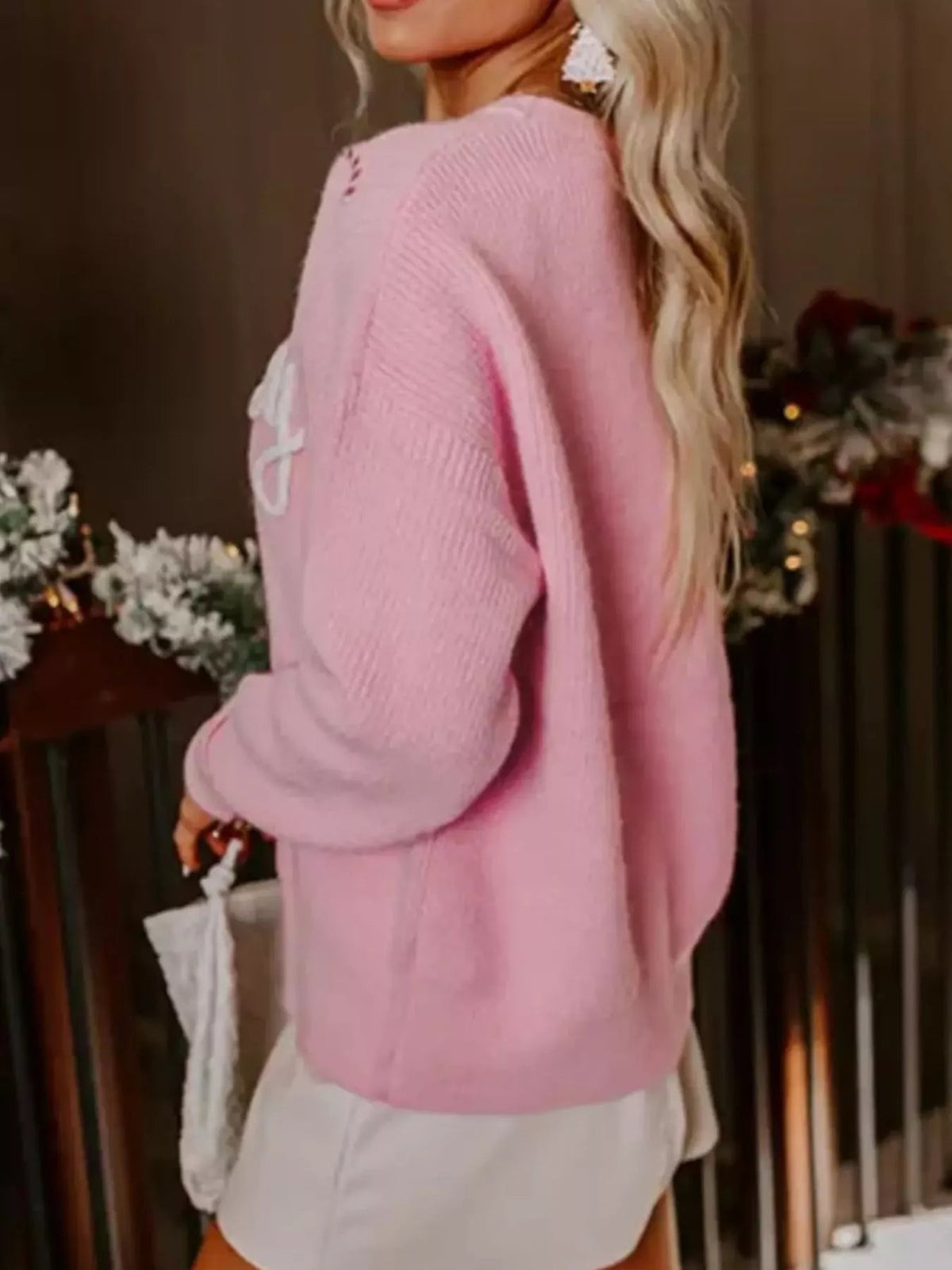 Wicked Thread Society pink embroidered crew neck sweater with candy cane design worn by a woman in a holiday setting