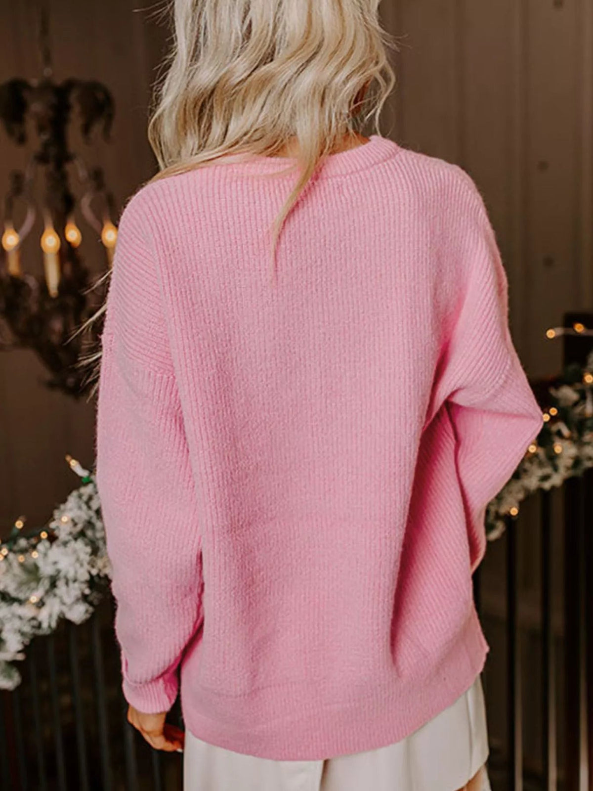 Back view of a blonde woman wearing a pink Wicked Thread Society crew neck sweater with ribbed knit texture