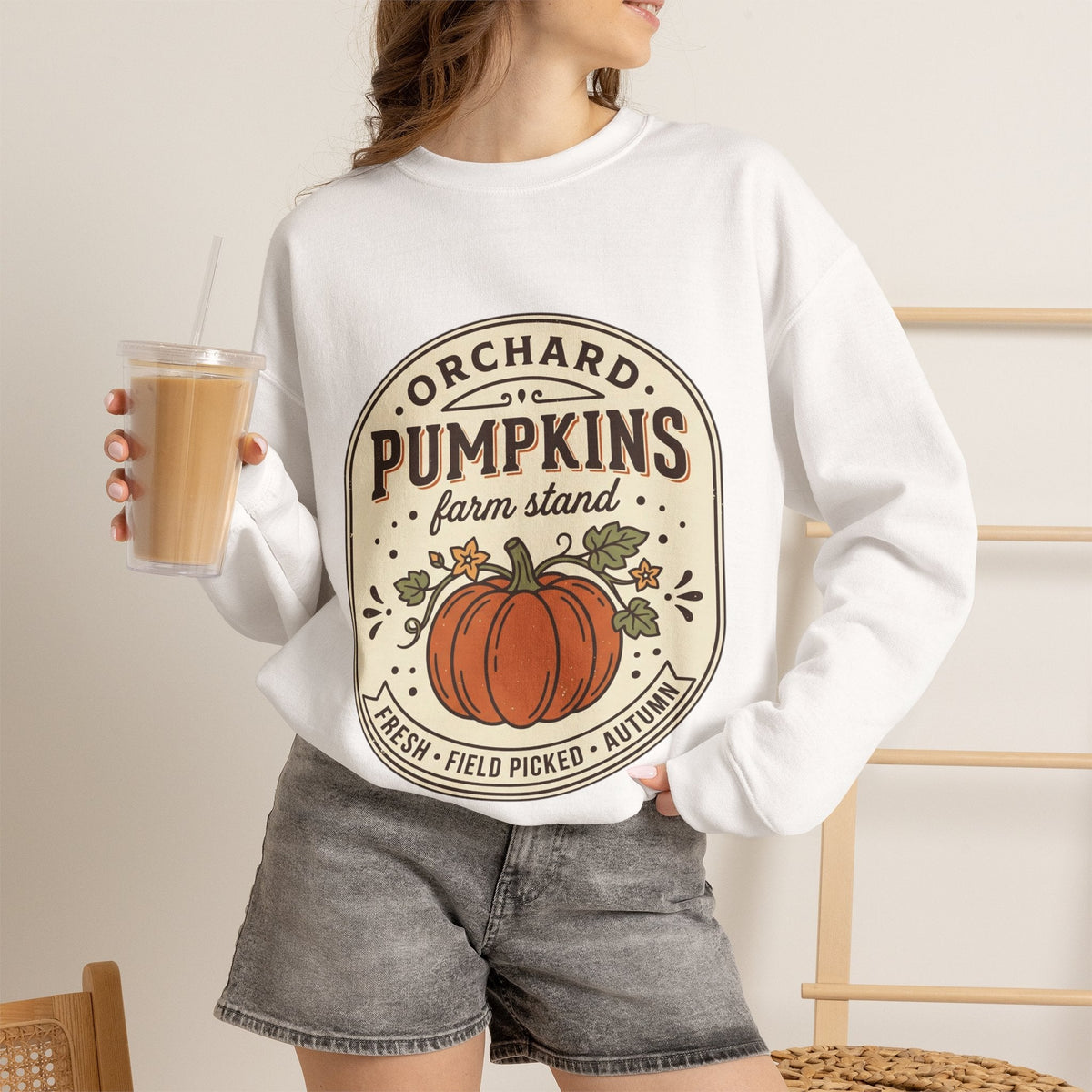 Wicked Thread Society white crewneck sweatshirt with a vintage pumpkin farmstand graphic, worn with grey denim shorts.