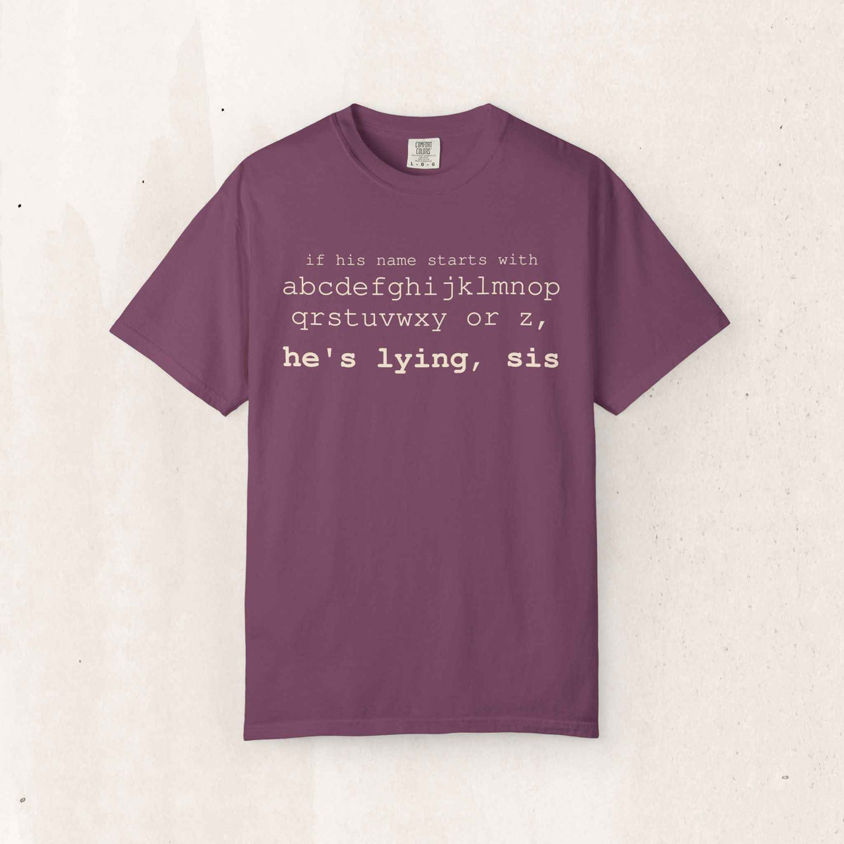 He's Lying, Sis Tee – Funny Alphabet Typography Shirt – Berry