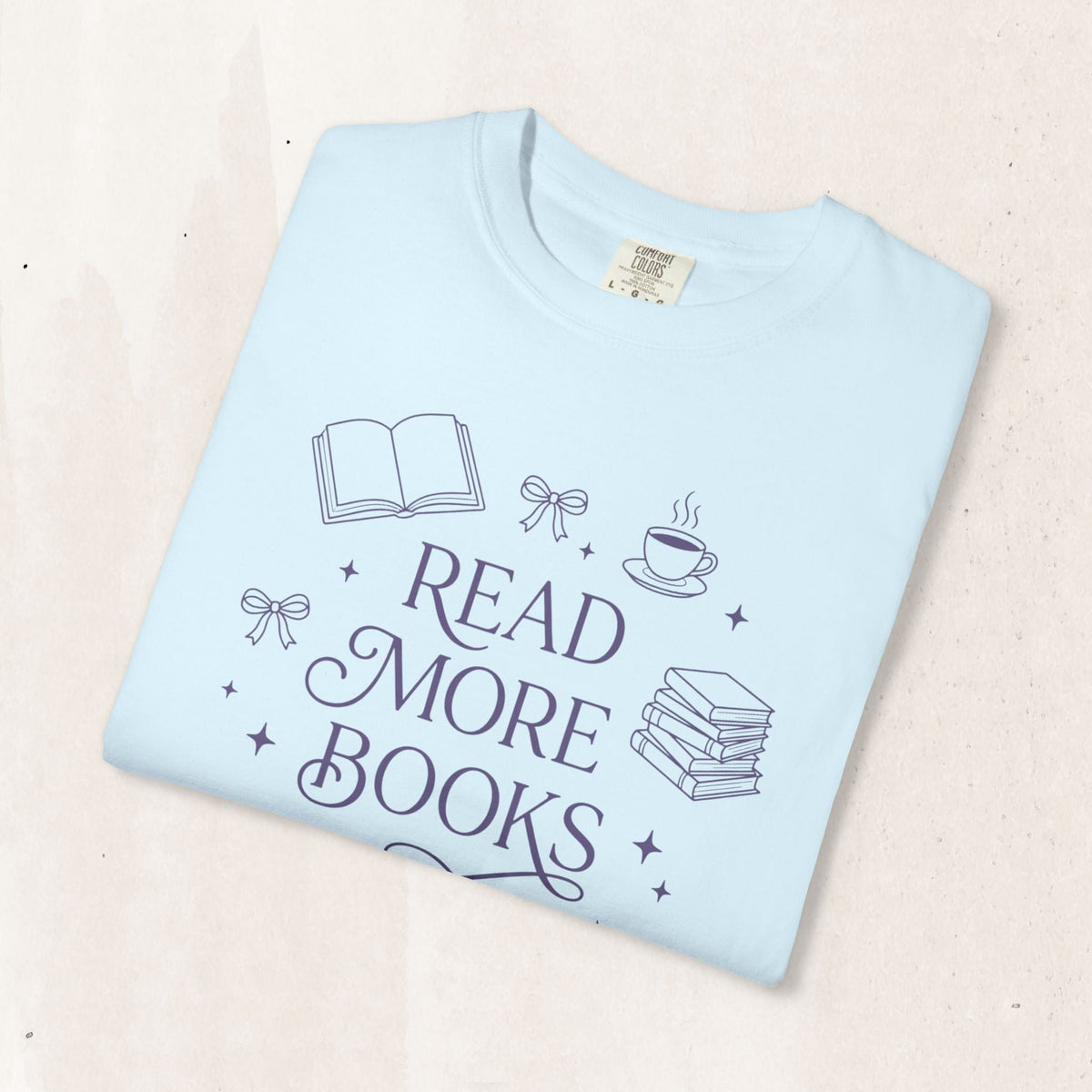 Wicked Thread Society light blue garment-dyed cotton t-shirt featuring a Read More Books graphic with book icons.