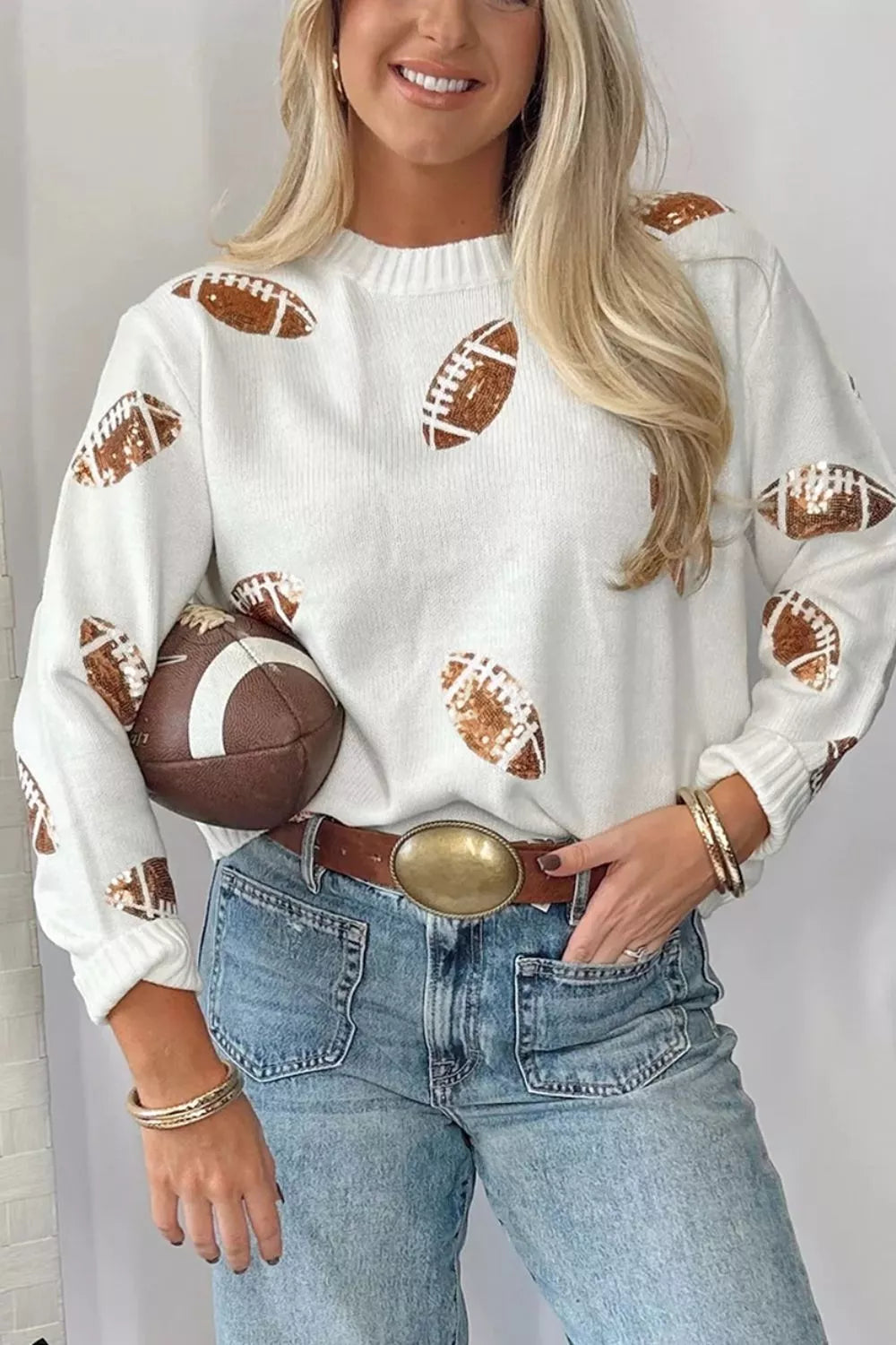 Wicked Thread Society white long sleeve sweater with brown sequin football patterns, worn with jeans and a belt.